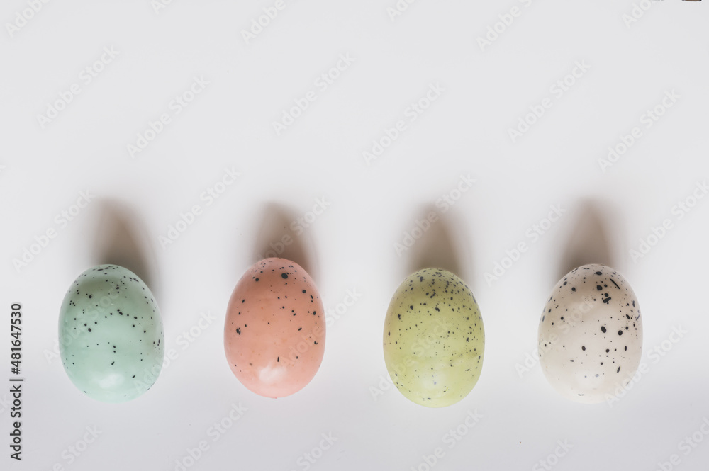 Four colored speckled eggs on white background - obrazy, fototapety, plakaty 