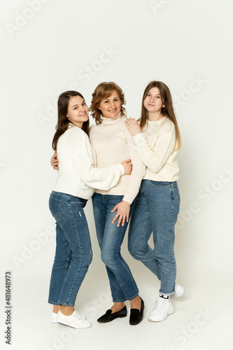 three girls stand on a white background in the studio and look at the camera. group portrait. mother with daughters on a white background.