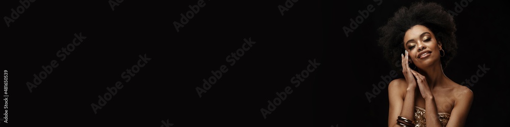 Fototapeta premium Smiling young african woman in dress standing
