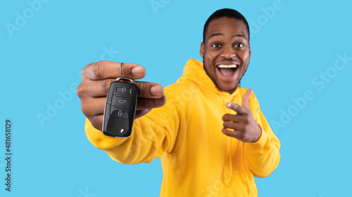 Excited Black Man Showing New Car Key On Blue Background © Prostock-studio