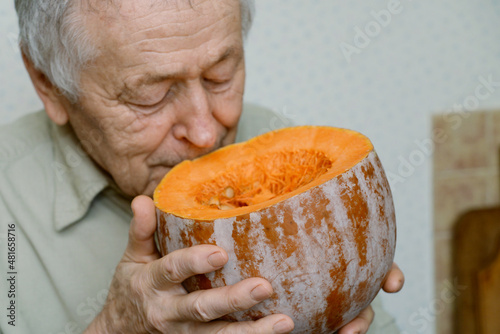 senior man smelling cut pumpkin