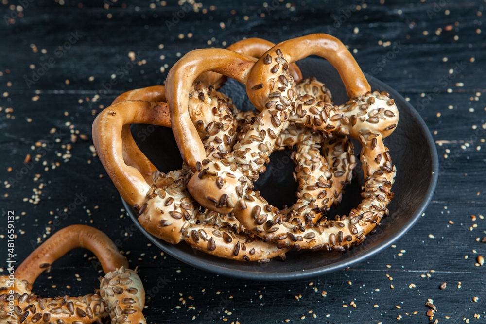Fresh prepared homemade soft pretzels. Different types of baked pretzels with seeds on a black background