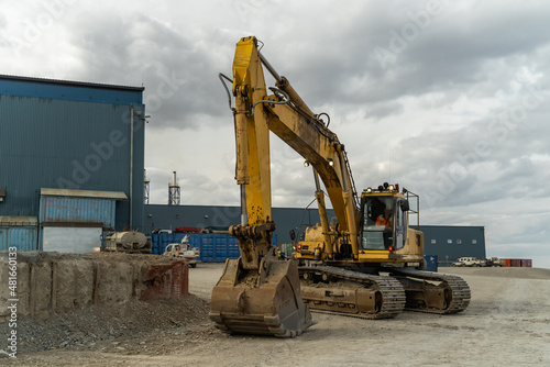 An excavator waiting for work in front of a blue building. Gold mining site.