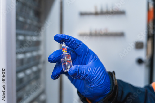 photo of a hand with blue surgical gloves holding a vial of medication. in the background you can see the ampullary of the ambulance photo