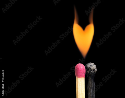 Flaming heart over two matchsticks on black