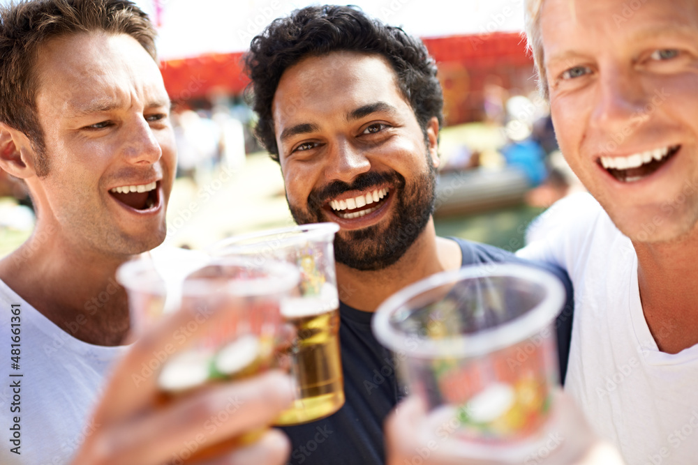 Let's get this party started. Three young men toasting their beers at a music festival.