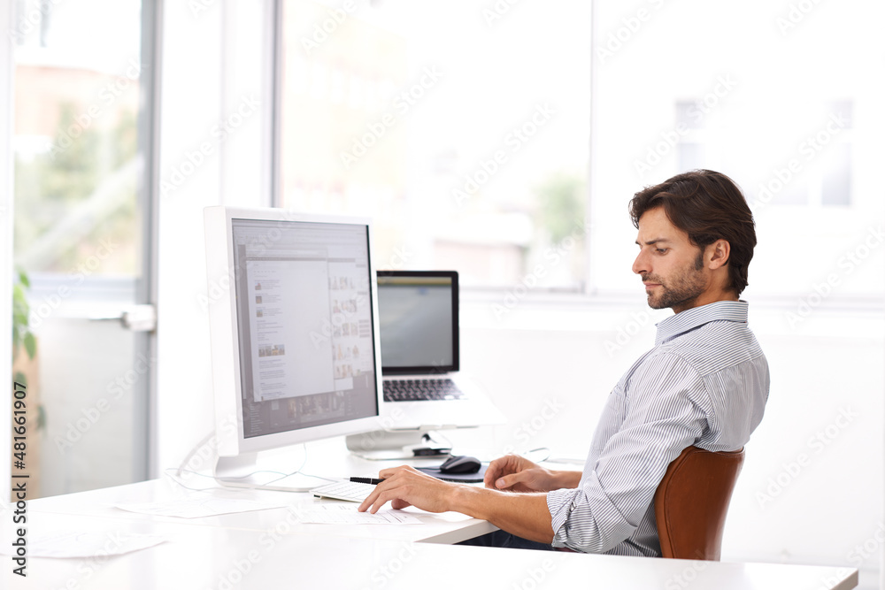 Designing is serious business. Shot of a handsome man working on a computer in an office. Designing is serious business. Shot of a handsome man working on a computer in an office.