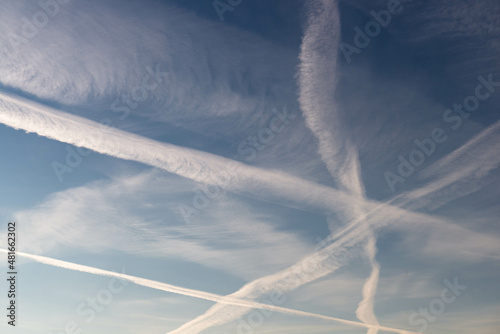 Chmury kondensacyjne po przelocie samolotu na błękitnym niebie.