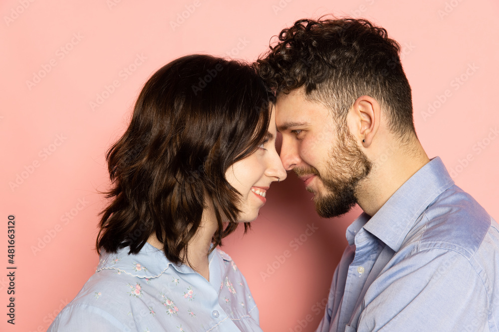 Closeup young and happy man and woman look at each other isolated on pink trendy color background. Human emotions, youth, love and lifestyle concept Closeup young and happy man and woman look at each other isolated on pink trendy color background. Human emotions, youth, love and lifestyle concept
