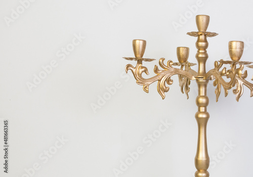 Golden baroque candlestick on a light background. Gold candlestick made of wood and metal made by hand. 