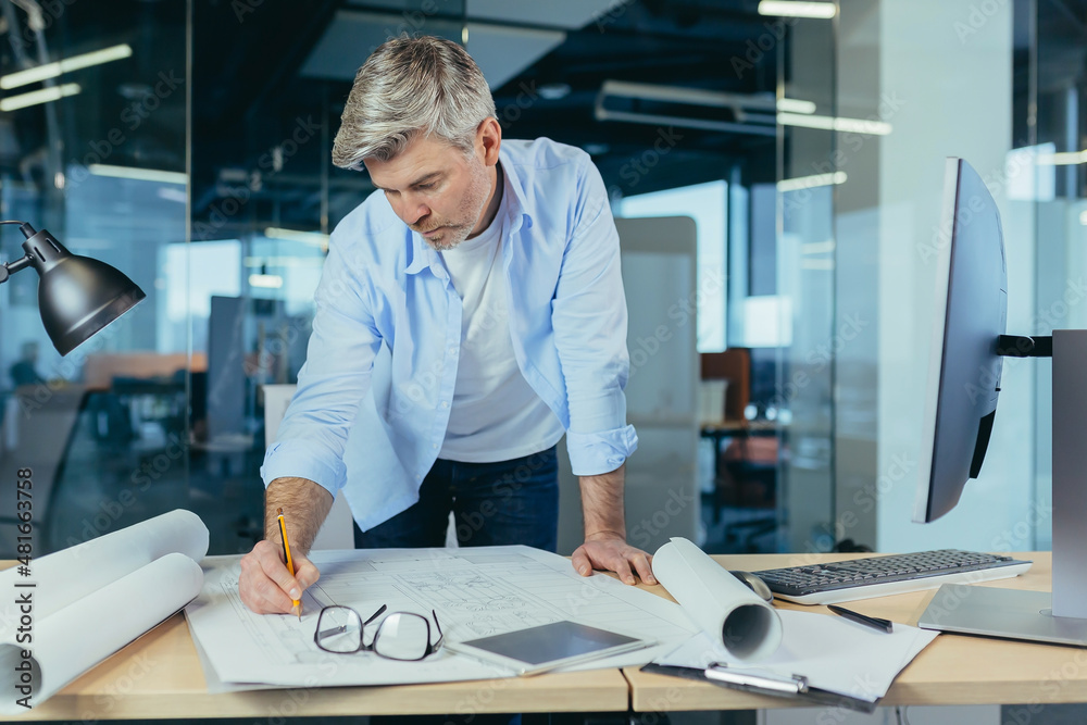 An experienced architect working on a drawing, a man in a modern office at the computer, a designer draws a modern project An experienced architect working on a drawing, a man in a modern office at the computer, a designer draws a modern project