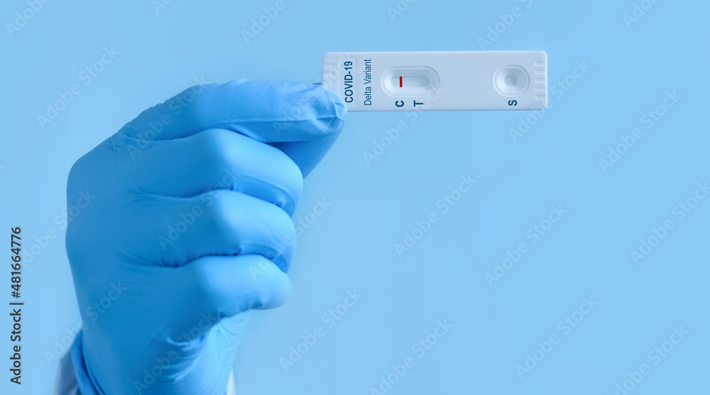 Doctor's hand in medical gloves shows a rapid laboratory test for COVID-19 Delta variant strain to detect IgM and IgG antibodies to the new coronavirus. The test shows a negative result.