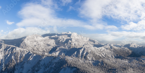 Aerial Panoramic View of Canadian Mountain covered in snow. Colorful Blue Sky with Clouds Art Render. Located near Squamish, North of Vancouver, British Columbia, Canada. Nature Background Panorama