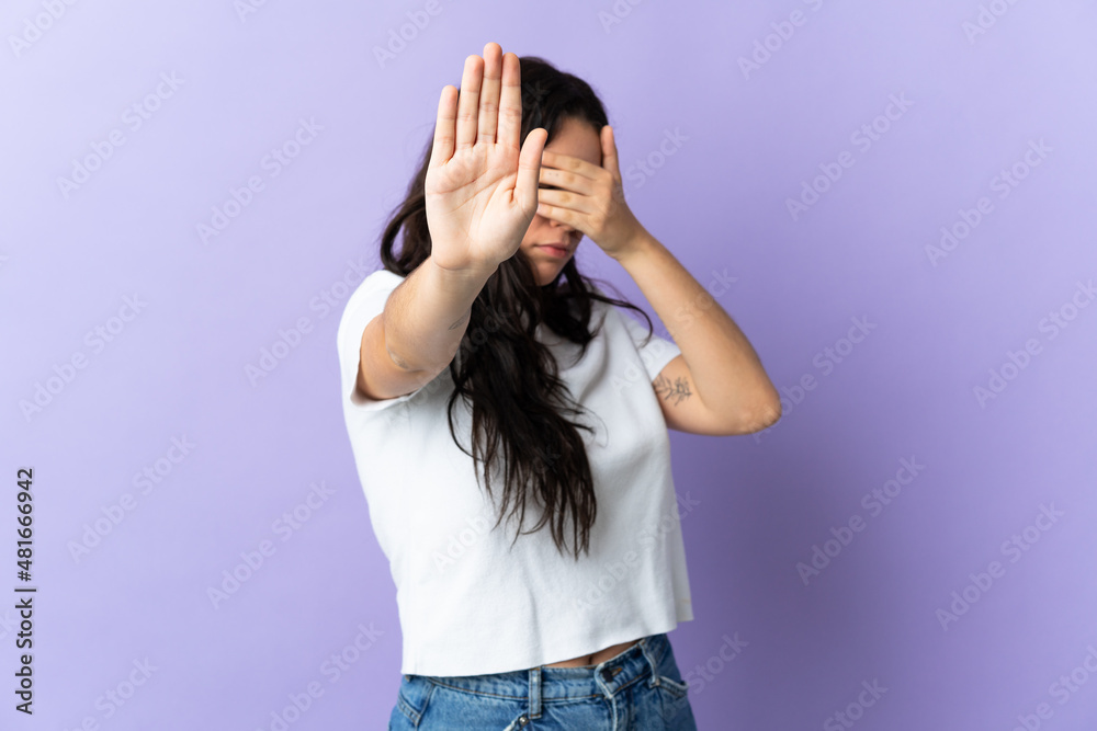 Young caucasian woman isolated on purple background making stop gesture and covering face