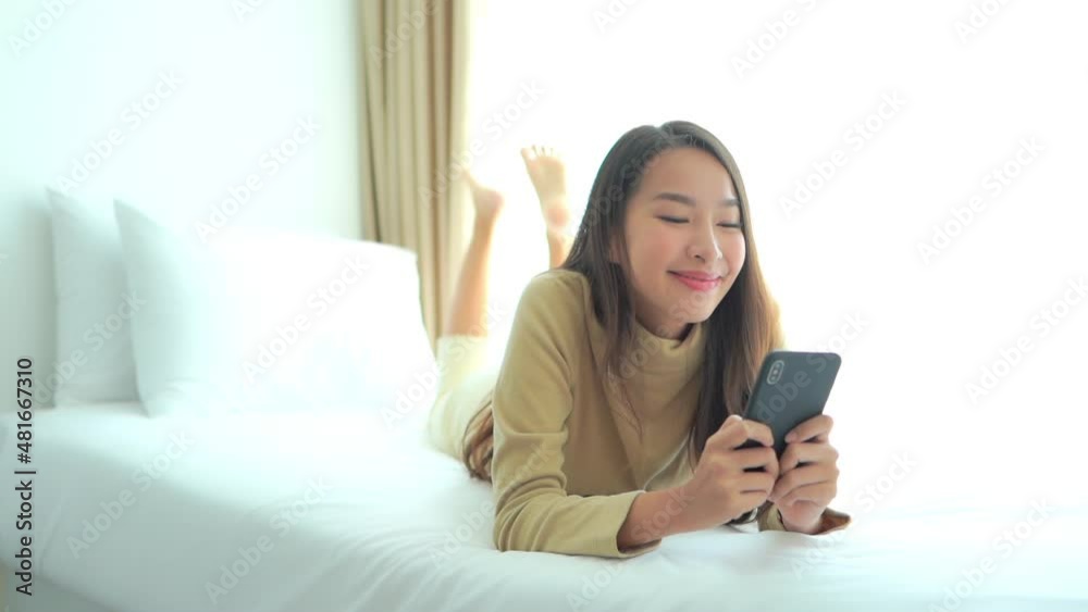 Close-up of a young woman lying on a bed as she types into her smartphone. Title space Close-up of a young woman lying on a bed as she types into her smartphone. Title space