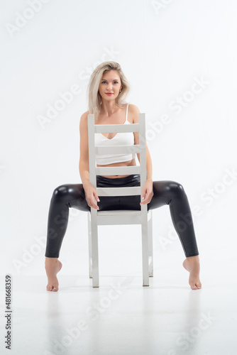 Beautiful blonde girl sitting on a chair in a bright studio