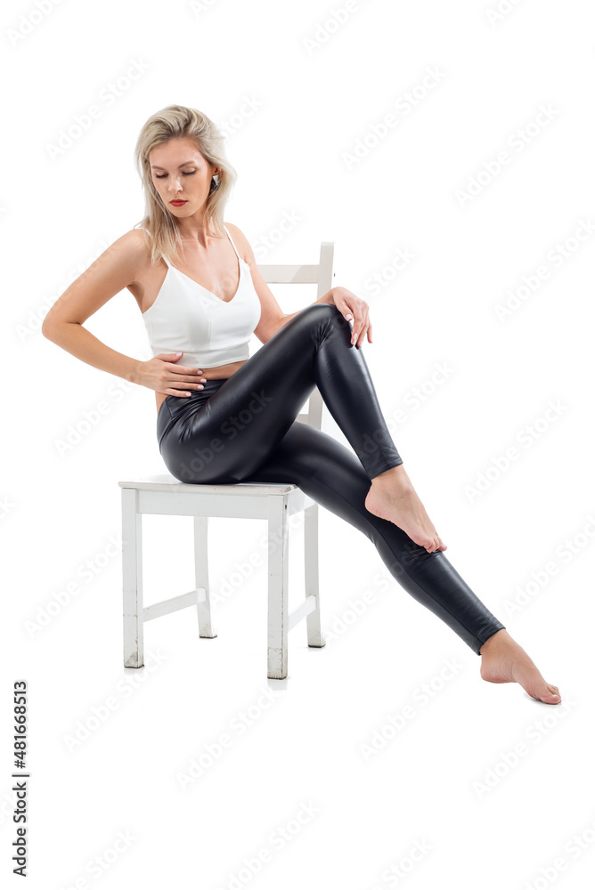 Fototapeta premium Beautiful blonde girl sitting on a chair in a bright studio