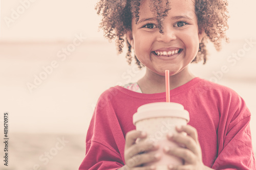 Portrait of cheerful african american pretty child drinking smoothie, smiling at camera, outdoor, copy space. photo