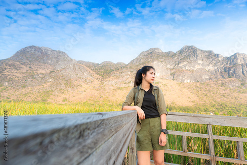 Freedom traveler woman standing with raised arms and enjoying a beautiful nature and cheering young woman backpacker at sunrise seaside mountain peak 