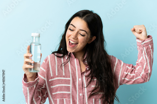 Murais de parede Young woman with a water isolated on blue background celebrating a victory