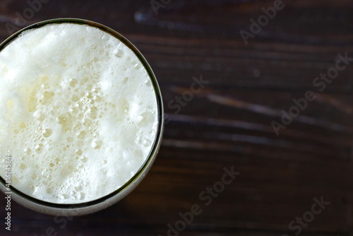 a large glass of cold light beer with foam on a dark background. St.Patrick 's Day