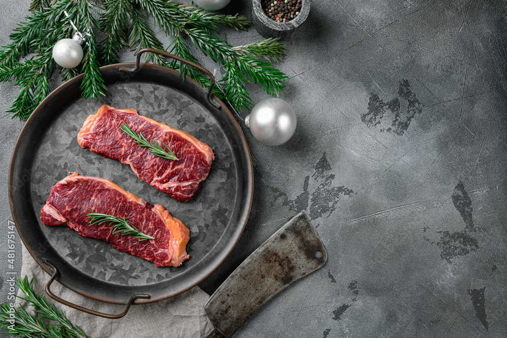 Raw New York striploin beef steak to the Christmas and New Year, on gray stone table background, top view flat lay, with copy space for text