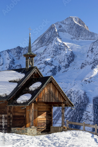 The littel wooden St Anna Chapel on the high mountain of Hockenalp with Bietschhorn mountains Alps peak in winter, Loetschental, Canton Valais, Switzerland