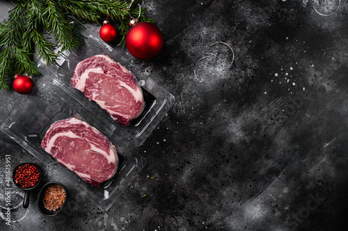 Marbled beef from the store for the new year, on black dark stone table background, top view flat lay, with copy space for text