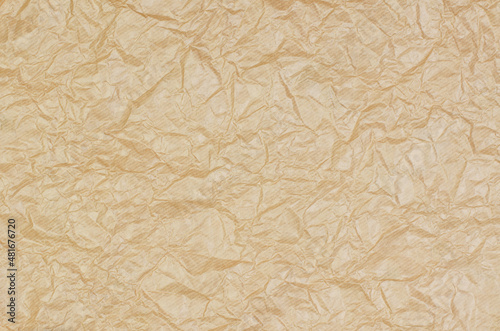 Background from crumpled parchment paper. Brown wrinkled paper as background