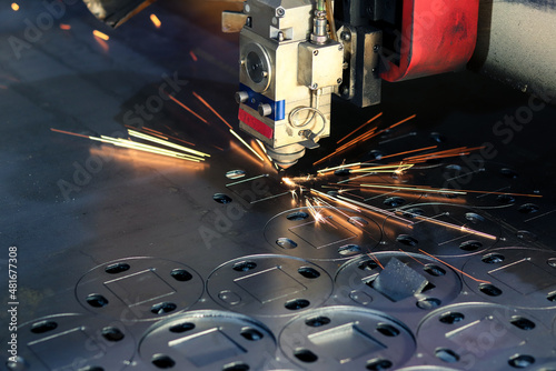 The laser machine cuts a metal sheet and bright sparks fly out of its work. Laser machine at a metalworking factory