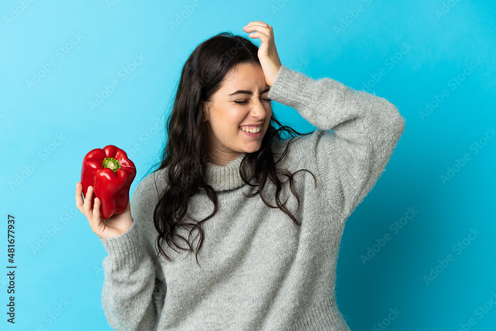 Young caucasian woman holding a pepper isolated on blue background has realized something and intending the solution Young caucasian woman holding a pepper isolated on blue background has realized something and intending the solution