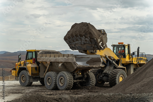 A loader loads ore into an articulated dump truck. photo