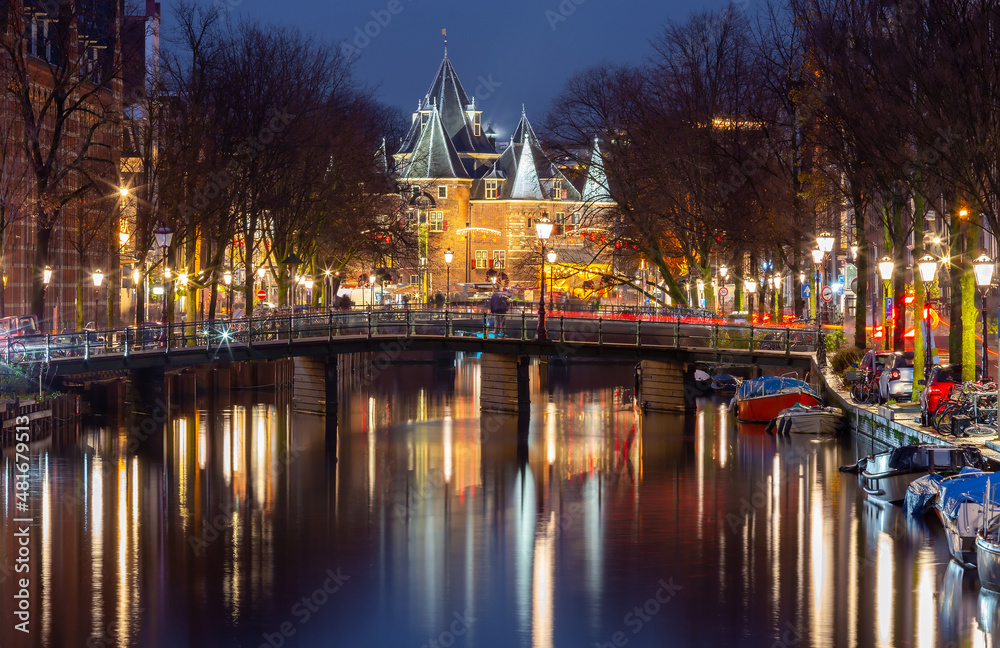 Obraz premium Beautiful old houses on the city waterfront of Amsterdam at sunset.