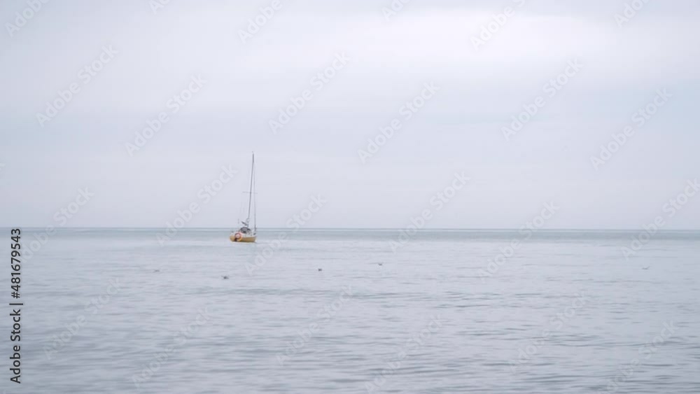 Seascape. A small lonely yellow yacht bobs on the waves in cloudy stormy weather. Gray cloudy sky and gray sea water surface. Skyline. Sea landscape one boat sea waves. Natural background Seascape. A small lonely yellow yacht bobs on the waves in cloudy stormy weather. Gray cloudy sky and gray sea water surface. Skyline. Sea landscape one boat sea waves. Natural background