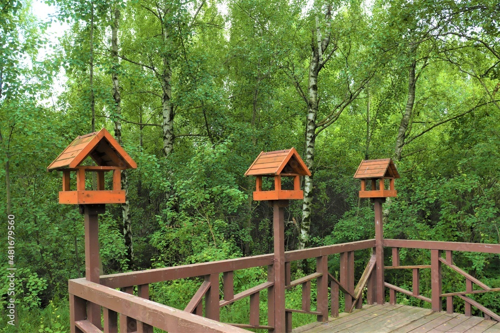Three wooden feeders for wild birds and animals on a walking trail in Dolgiye Prudy Park in the north of Moscow.