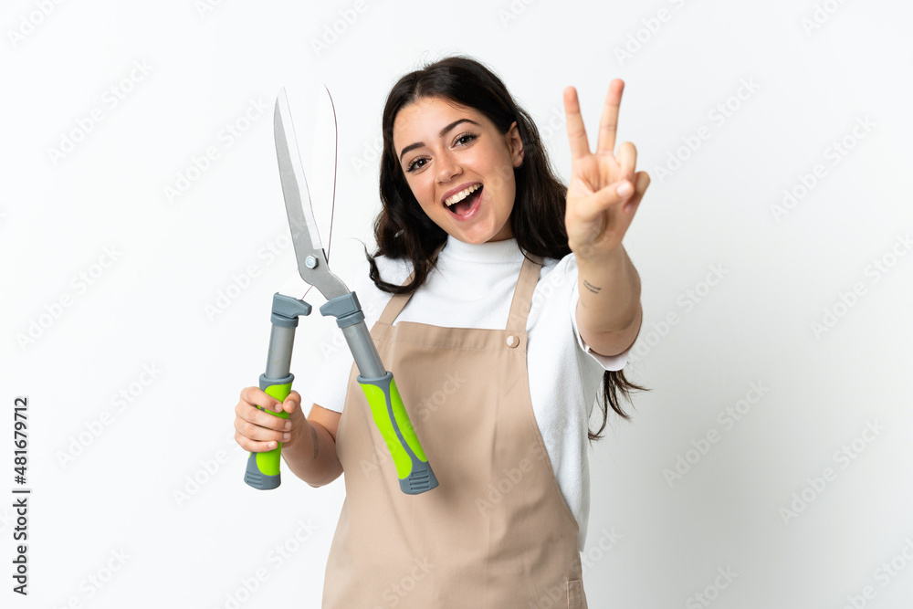 Young caucasian woman holding a plant isolated on white background smiling and showing victory sign Young caucasian woman holding a plant isolated on white background smiling and showing victory sign