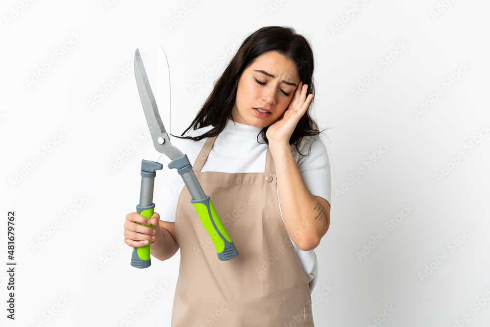 Young caucasian woman holding a plant isolated on white background with headache Young caucasian woman holding a plant isolated on white background with headache