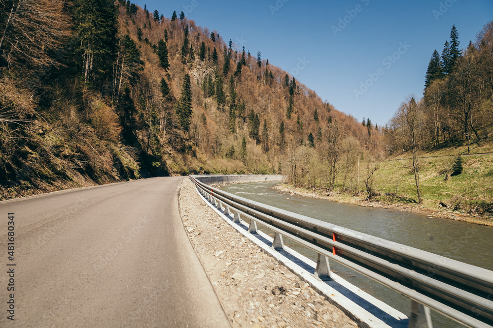 Fototapeta premium Mountain road trouble river, mixed forest and fence