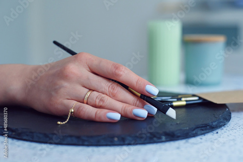 Close up female hand holding paint brush at modern studio.