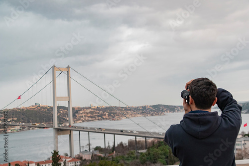 Young boy taking bosphorus bridge and marmara sea. Back view photo. Winter nature . Hobby and leisure time activity.