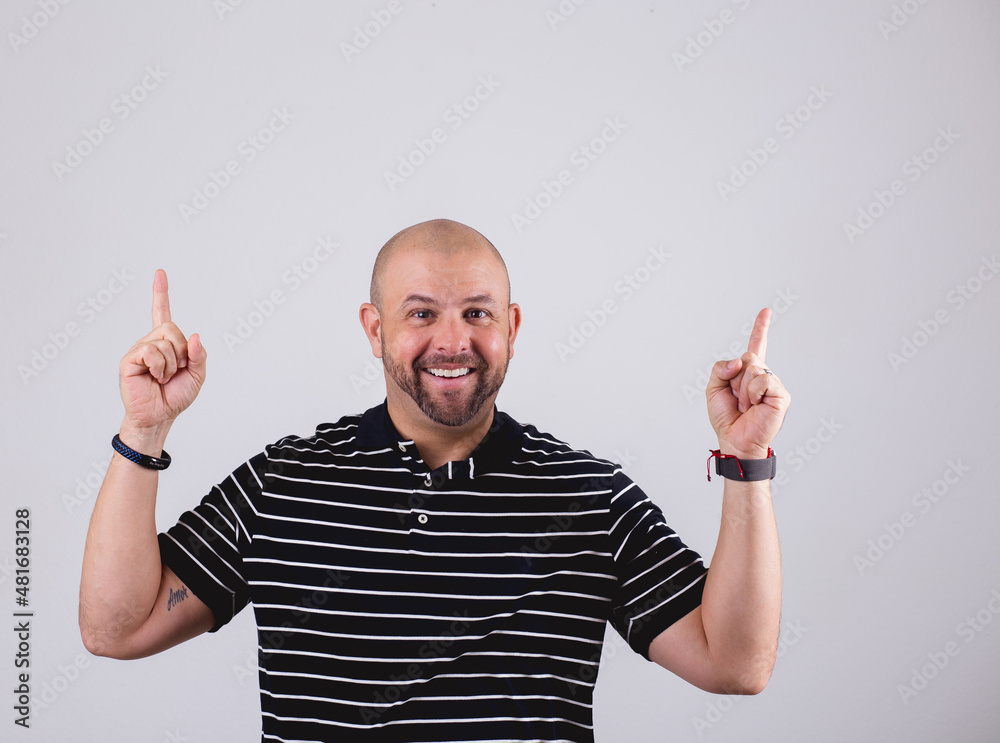 Hispanic bald man standing in front of a white background and making emotional gestures Hispanic bald man standing in front of a white background and making emotional gestures