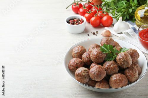 Tasty cooked meatballs with parsley on white wooden table. Space for text