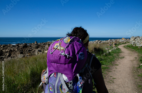 A pilgrim walks the Portuguese Camino de Santiago along the coast with a large backpack photo