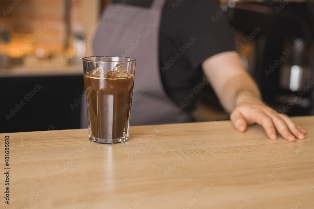 Barista at counter with glass of cold coffee Barista at counter with glass of cold coffee