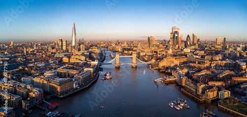 Panoramic aerial view of the skyline of London, England, with Tower Bridge and the skyscrapers of the City in golden sunrise light