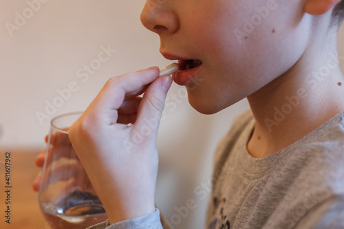 A child taking a pill and holding a glass of water photo