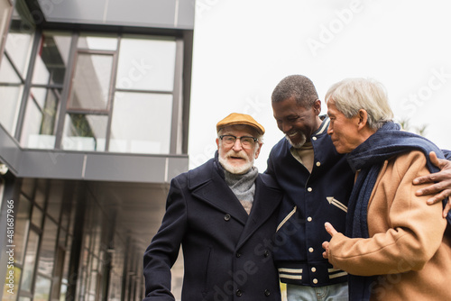 Senior african american man hugging multiethnic friends on urban street.