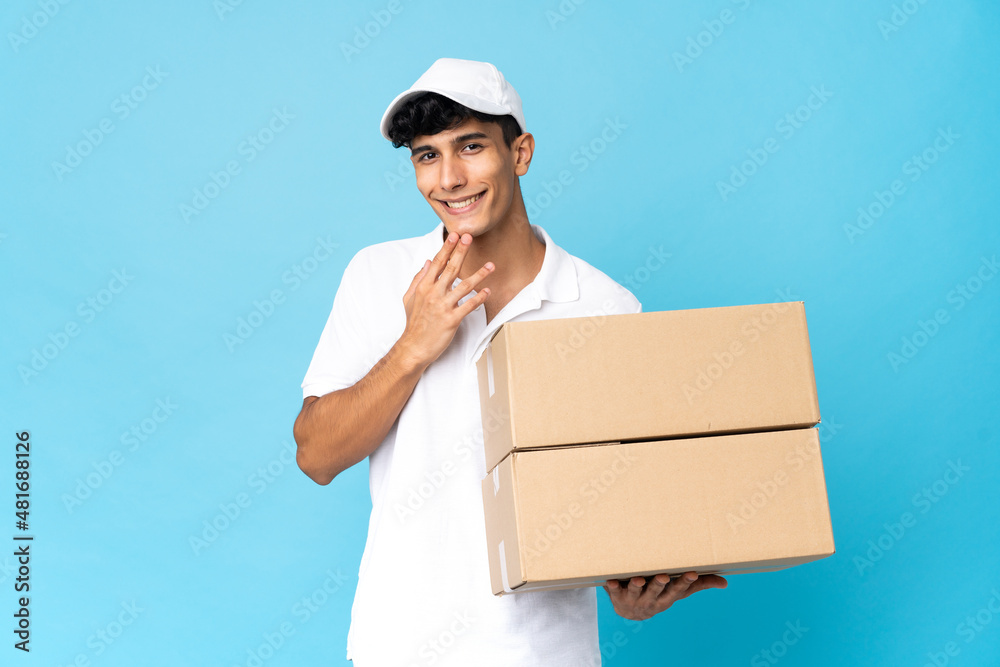 Delivery Argentinian man isolated on blue background looking up while smiling Delivery Argentinian man isolated on blue background looking up while smiling