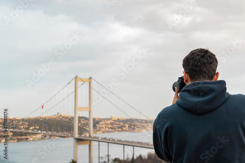Young boy taking bosphorus bridge and marmara sea. Back view photo. Winter nature . Hobby and leisure time activity.
