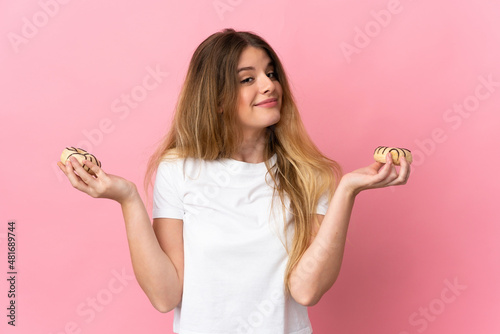 Young blonde woman isolated on pink background holding donuts